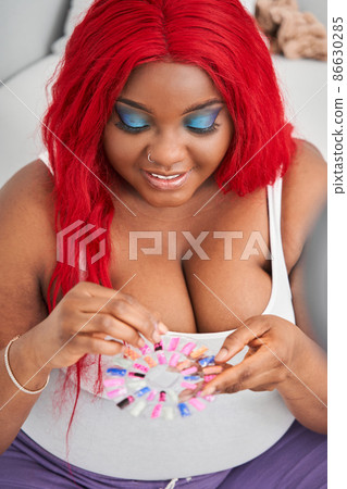 Woman choosing finger nails polish with excited emotions while preparing creative manicure at home 86630285