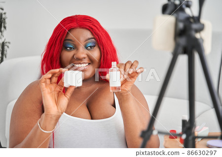 Woman celling cosmetics in internet while showing it to the smartphone camera with toothy smile Woman celling cosmetics in internet while showing it to the smartphone camera with toothy smile 86630297