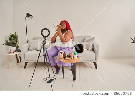 Woman blogger is showing how to make up and use cosmetics in front of the camera while sitting 86630798
