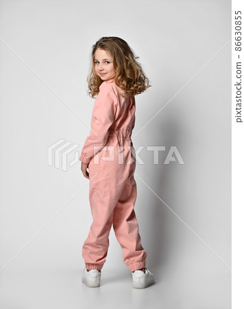 girl in a pink cotton jumpsuit stands with her girl in a pink cotton jumpsuit stands with her 86630855