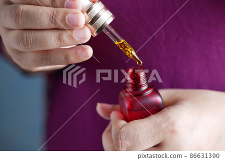 women hand Drop falls from a pipette into a cosmetic bottle women hand Drop falls from a pipette into a cosmetic bottle 86631390