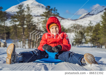 happy and positive little boy enjoying sledding and cold weather outdoor, winter fun activity concept 86631392