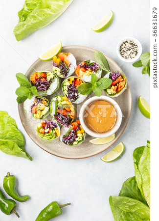 Vegan rainbow-colored spring rolls served with peanut sauce 86631679
