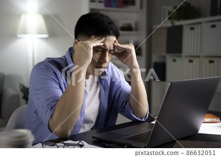 Asian man looking at laptop screen with serious and worried face hand on forehead working from home. Asian man looking at laptop screen with serious and worried face hand on forehead working from home. 86632051