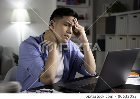 Asian man looking at laptop screen with serious and worried face hand on forehead working from home. 86632052