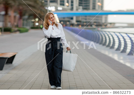 Young woman at the street with shopping bags talking on mobile phone Young woman at the street with shopping bags talking on mobile phone 86632273
