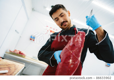 Butcher man holding meat on hook to cut and sell it 86633902