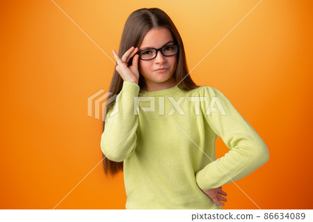 Funny caucasian teen girl in eyeglasses isolated on orange background Funny caucasian teen girl in eyeglasses isolated on orange background 86634089