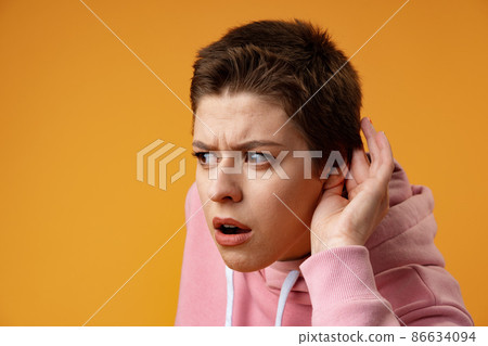 Young girl doing listen gesture with hand on ear over yellow background Young girl doing listen gesture with hand on ear over yellow background 86634094