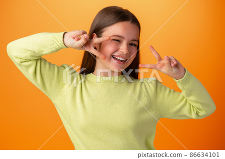 Teenager girl isolated on orange background showing victory sign Teenager girl isolated on orange background showing victory sign 86634101