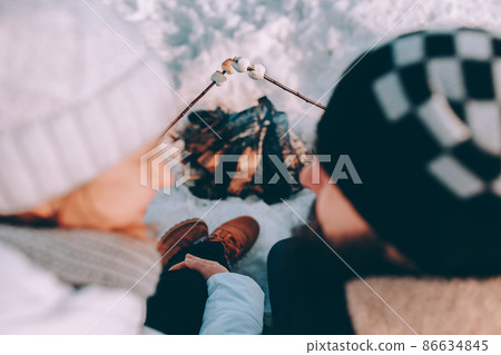 Couple in love fry marshmallows at stake. winter theme Couple in love fry marshmallows at stake. winter theme 86634845