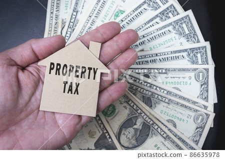 Property tax text on brown paper house model with background of dollar banknotes Property tax text on brown paper house model with background of dollar banknotes 86635978