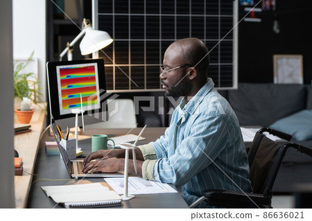 African architect with disability sitting at his workplace and typing on laptop, he working with online project at home African architect with disability sitting at his workplace and typing on laptop, he working with online project at home 86636021