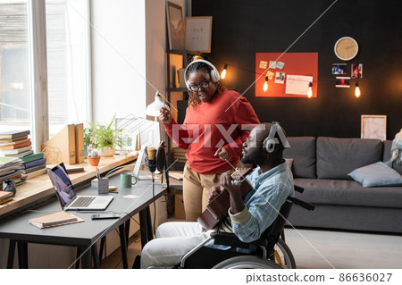 African young couple performing together during online broadcasting, woman singing a song with man with disability who playing guitar 86636027