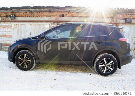 Toyota Raw4 against the background of brick garage and rusty metal doors on a sunny winter morning. Toyota Raw4 against the background of brick garage and rusty metal doors on a sunny winter morning. 86636071