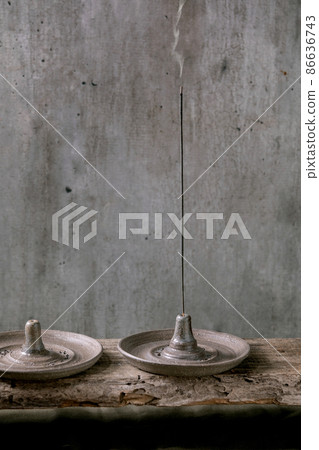 Incense stick in hand crafted gray ceramic incense holder 86636743