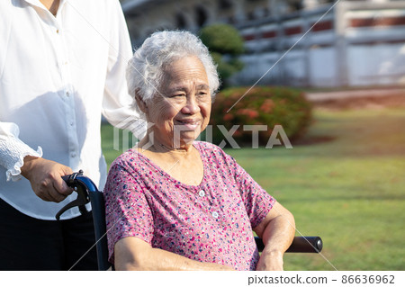 Caregiver help and care Asian senior or elderly old lady woman patient sitting on wheelchair in park, healthy strong medical concept. Caregiver help and care Asian senior or elderly old lady woman patient sitting on wheelchair in park, healthy strong medical concept. 86636962