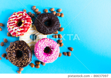 Donut with hazelnuts on blue background, close up 86637097