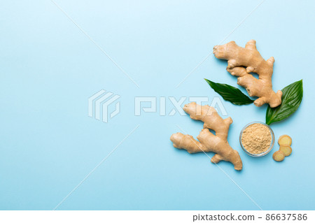 Finely dry Ginger powder in bowl with green leaves isolated on colored background. top view flat lay Finely dry Ginger powder in bowl with green leaves isolated on colored background. top view flat lay 86637586