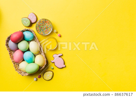 Colorful easter cookies in basket with Multi colors Easter eggs on colored background . Pastel color Easter eggs. holiday concept with copy space Colorful easter cookies in basket with Multi colors Easter eggs on colored background . Pastel color Easter eggs. holiday concept with copy space 86637617