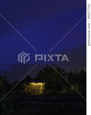 Star tracks over garden and gazebo illuminated with light bulbs. Long exposure of starry night sky. Star tracks over garden and gazebo illuminated with light bulbs. Long exposure of starry night sky. 86637792
