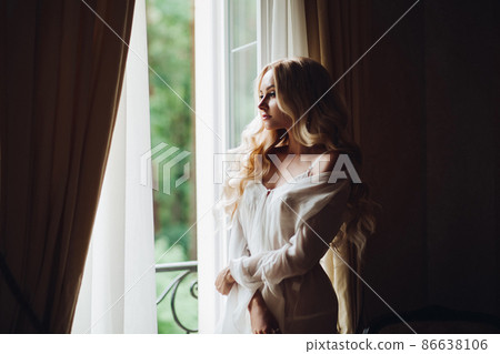 Gorgeous bride standing near balcony and looking Gorgeous bride standing near balcony and looking 86638106