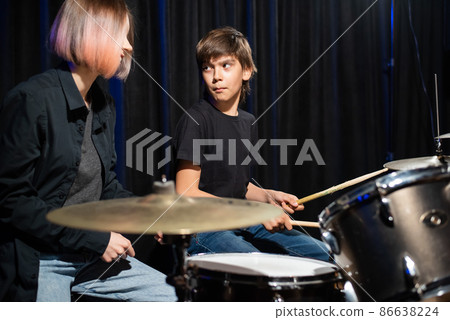 Young woman teaching boy to play drums. 86638224