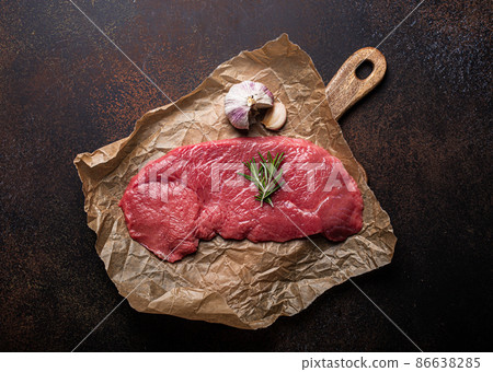 Beef lean raw fillet steak on baking paper with rosemary, garlic and spices 86638285