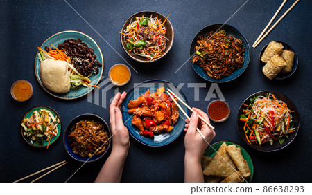 Set of Chinese dishes on table, female hands holding chopsticks Set of Chinese dishes on table, female hands holding chopsticks 86638293
