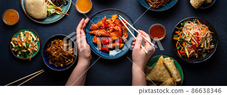 Set of Chinese dishes on table, female hands holding chopsticks Set of Chinese dishes on table, female hands holding chopsticks 86638346