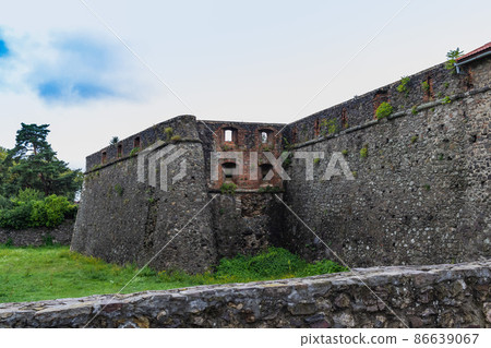 Medieval Gray Castle wall of ancient Uzhgorod castle with a green lawn in front. Uzhgorod castle, Zakarpattya region, Western Ukraine 86639067