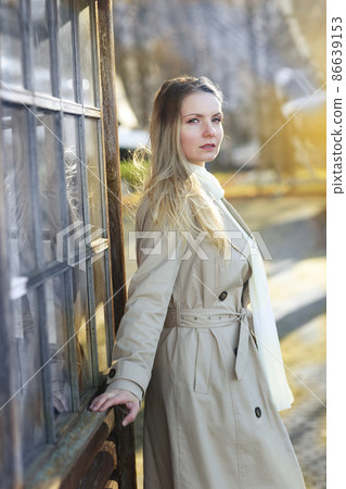 young blond slavic woman with long hair wearing trench coat closeup street portrait on city park background young blond slavic woman with long hair wearing trench coat closeup street portrait on city park background 86639153