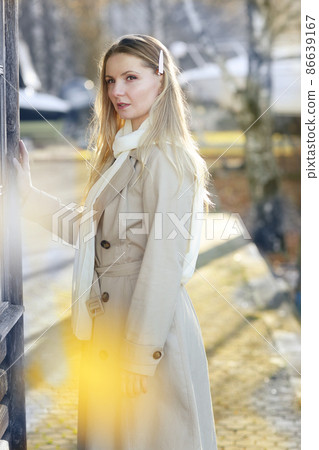 young blond slavic woman with long hair wearing trench coat closeup street portrait on city park background young blond slavic woman with long hair wearing trench coat closeup street portrait on city park background 86639167