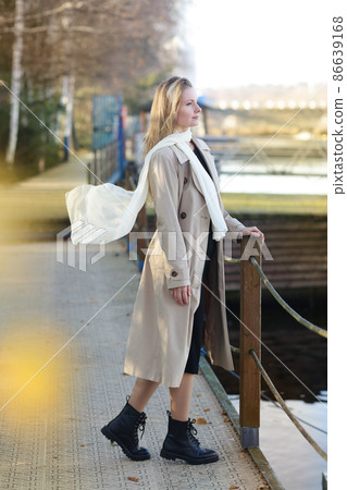 young blond slavic woman with long hair wearing trench coat closeup street portrait on city park background young blond slavic woman with long hair wearing trench coat closeup street portrait on city park background 86639168