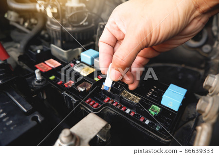 Mechanic replaces the spare fuse to the car fuse box with the fuse clip tool Mechanic replaces the spare fuse to the car fuse box with the fuse clip tool 86639333