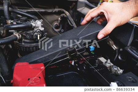 A mechanic hand is removing the fuse box from the automobile. A mechanic hand is removing the fuse box from the automobile. 86639334