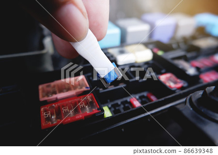 Mechanic replaces the spare fuse to the car fuse box with the fuse clip tool Mechanic replaces the spare fuse to the car fuse box with the fuse clip tool 86639348