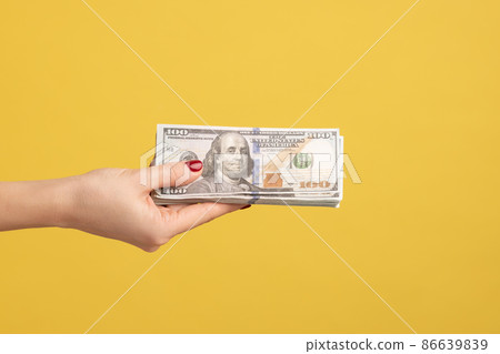 Profile side view closeup of woman hand holding and showing fan of american dollar money in hand. Indoor studio shot isolated on yellow background. 86639839