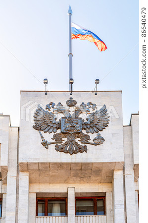 Russian coat of arms and the state flag on the building Russian coat of arms and the state flag on the building 86640479