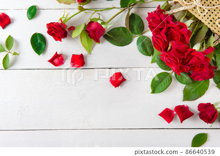 Pattern of red roses, petals and green leaves on a white . Abstraction for a postcard. Pattern of red roses, petals and green leaves on a white . Abstraction for a postcard. 86640539