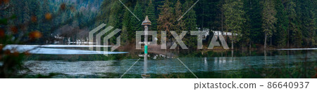 Alpine lake Synevyr, wooden statues near the lake, a tourist place in Ukraine, ice on the lake. 86640937