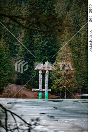 Alpine lake Synevyr, wooden statues near the lake, a tourist place in Ukraine, ice on the lake. 86640940