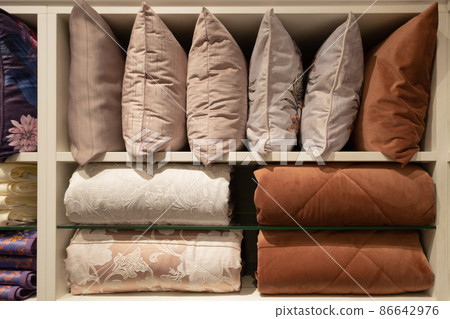 Blankets and pillows in the store. Neatly laid out on the shelves 86642976