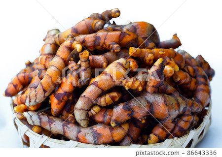 Turmeric roots on wooden spoon on white background. Turmeric roots on wooden spoon on white background. 86643336