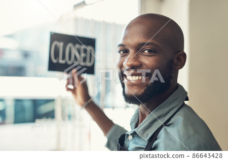 Were ready to show you our new stock. Shot of a handsome young man standing and turning the sign on the door to his bicycle shop. 86643428