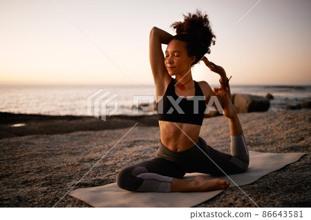 Yoga. Good for the mind, good for the body. Full length shot of an attractive young woman practicing yoga on the beach at sunset. 86643581