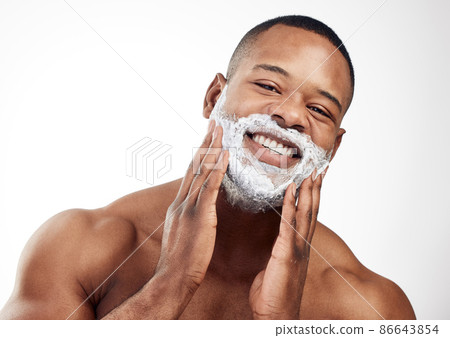 Forming a foamy cushion on the face before shaving. Studio portrait of a handsome young man applying shaving cream to his face against a white background. Forming a foamy cushion on the face before shaving. Studio portrait of a handsome young man applying shaving cream to his face against a white background. 86643854
