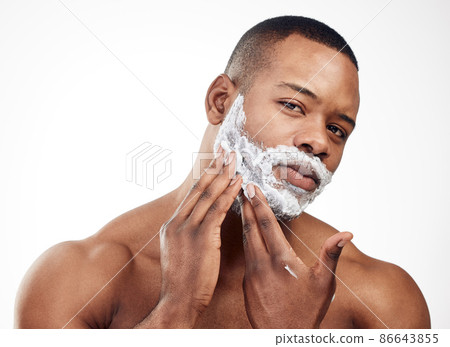 Shaving can give you a whole new look. Studio portrait of a handsome young man applying shaving cream to his face against a white background. Shaving can give you a whole new look. Studio portrait of a handsome young man applying shaving cream to his face against a white background. 86643855