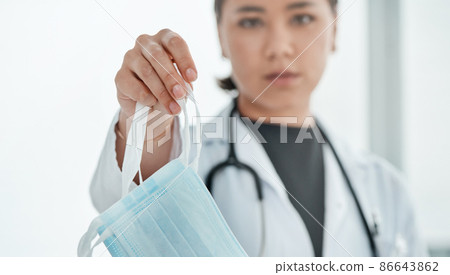 Were saving lives by advising everyone to wear masks. Cropped shot of a medical practitioner holding up a face mask. 86643862