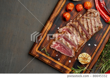 Keto ketogenic diet grilled fried beef steak, striploin on cutting board on dark brown table Keto ketogenic diet grilled fried beef steak, striploin on cutting board on dark brown table 86645332